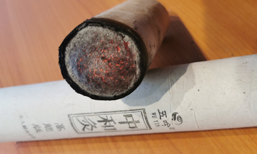 Close-up of a glowing moxa stick (mugwort) emitting therapeutic smoke